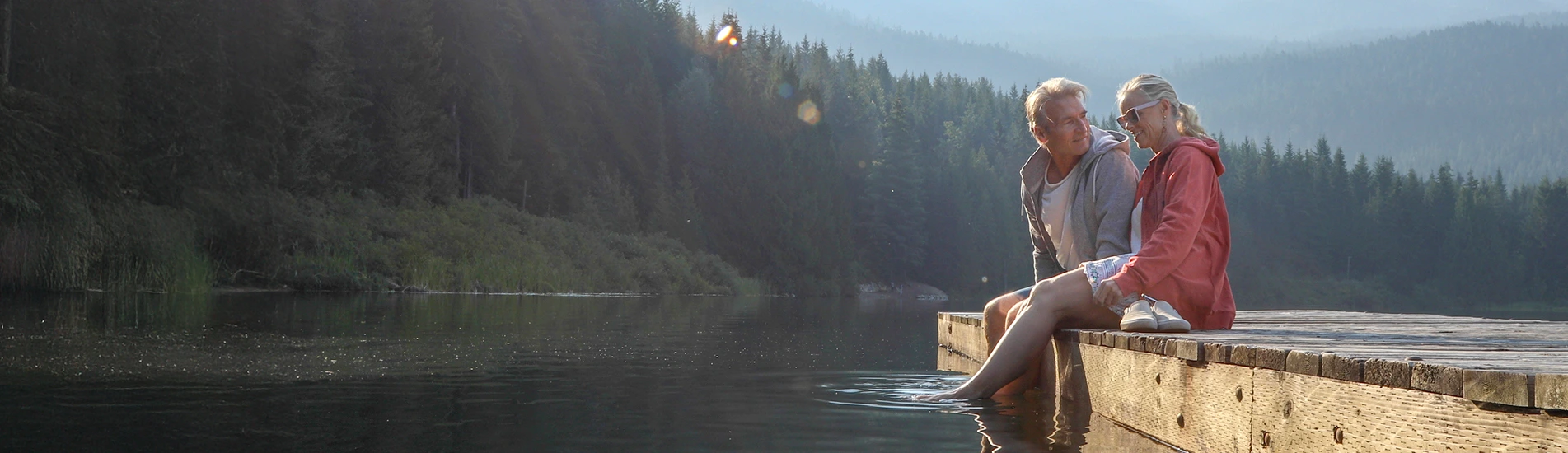 A couple sitting on a dock at a lake